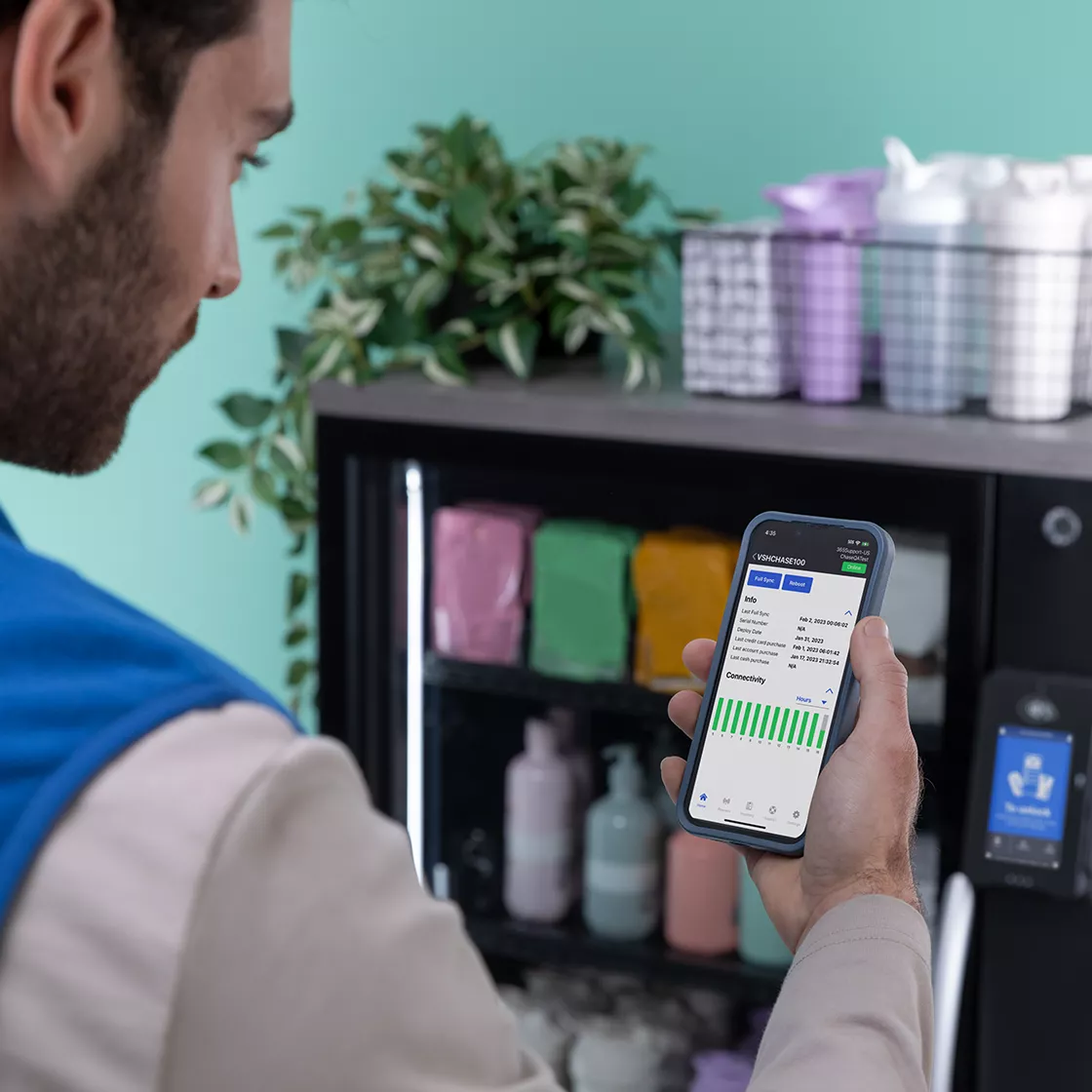 Operator looking at data on his phone to stock vending machine